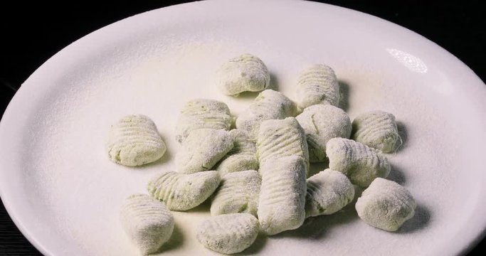 Gnocchi di patate verdi da cuocere con basilico fresco su un vassoio ruotante da esposizione
