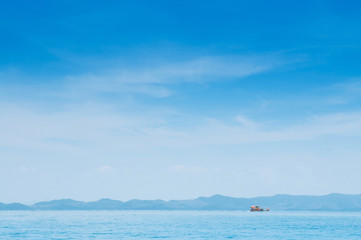 Fototapeta na wymiar Wide Phuket vibrant turqoise blue sea with fishing boat in far distance