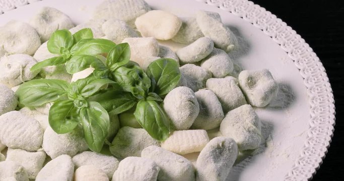 Gnocchi di patate verdi da cuocere con basilico fresco su un vassoio ruotante da esposizione