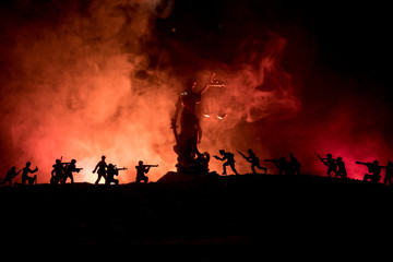 Naklejka na ściany i meble War - no justice concept. Military silhouettes fighting scene and The Statue of Justice on a dark toned foggy background.