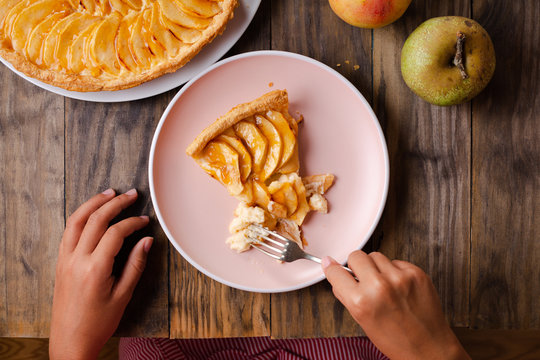 Girl Hands Eating A Portion Of Apple Pie Tart On Rustic Wooden Table