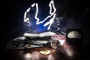 Energy for mining cryptocurrency. The energy meter with bitcoin and money on dark toned foggy...
