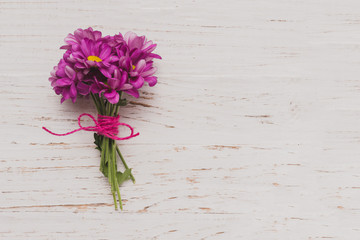 Purple flowers tied on white wooden surface