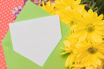 Close-up of piece of paper on envelope and yellow daisies