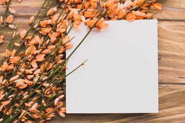 Blank paper with flowers on wooden surface