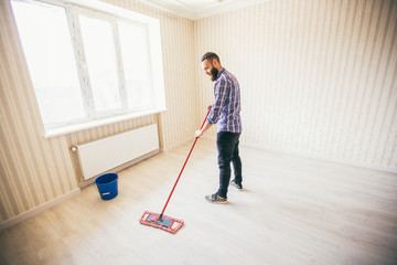 Fototapeta na wymiar Young bearded man makes cleaning the house