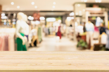Empty wood table with woman fashionable boutique clothing store window display in shopping mall