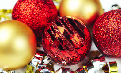 Shiny Christmas balls red and golden with confetti of foil. Close up. The concept of festive mood.