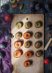 Fresh organic plums and plum slices on wooden board and rustic wooden table, autumn harvest, seasonal fruits, healthy lifestyle, top view, selective focus