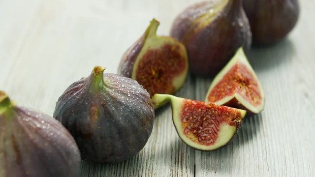 Closeup shot of row of figs with cut one on white wooden table 