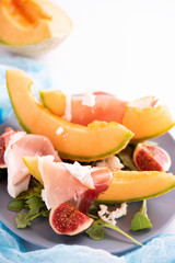 Close up of plate with melon, arugula and prosciutto
