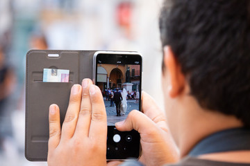 Ragazzo che fotografa la sposa e lo sposo con lo smartphone