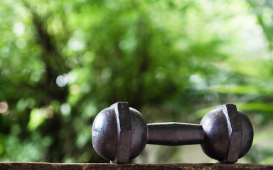 Black steel dumbbell with green garden background