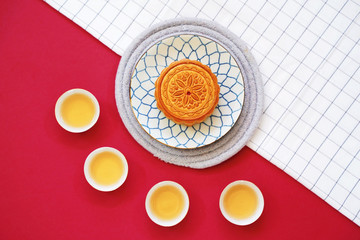 Flat lay of chinese moon cake with hot tea and on table cloth with red background, holiday and festival concept