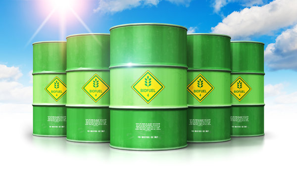 Group of green biofuel drums against blue sky with clouds and sun light