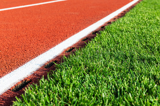 Red Running Track And Green Grass Field At The Sport Stadium