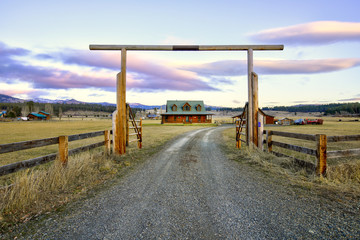 Entry gate to a nice wooden ranch home with beautiful landscape. - obrazy, fototapety, plakaty