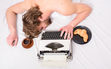 Man with typewriter coffee lay bed. Man sleepy lay bedclothes while work. Writer used old fashioned typewriter. Workaholic fall asleep. Author tousled hair fall asleep while write chapter top view