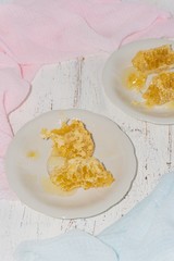 two white dessert plates with pieces of honeycomb on a light wooden background
