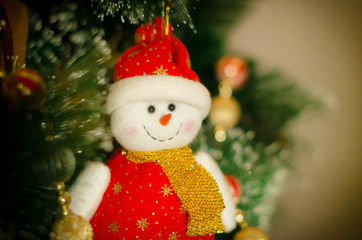 The toy in the form of a snowman hangs on the Christmas tree covered with hoarfrost. Christmas, New Year. Blurred background.
