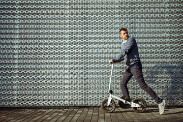 Side view of man pushing kick scooter while riding on beautiful embankment