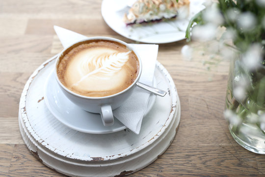 Fototapeta Cappuccino. Filiżanka gorącej kawy z pięknym zdobieniem na piance.