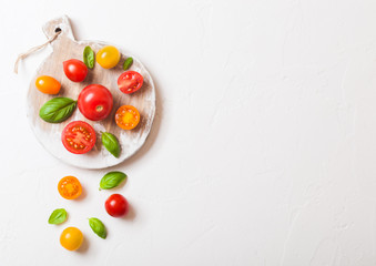 Naklejka na ściany i meble Organic Mini Tomatoes with basil and pepper on chopping board on stone kitchen background. San Marzano, orange and plum tomatoes