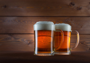 Two glasses of golden beer on wooden background