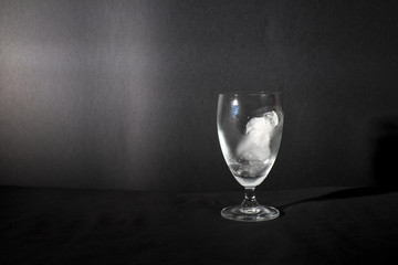 Ice cube melting in wine glass isolated in black background