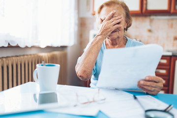 Elderly woman looking at her utility bills