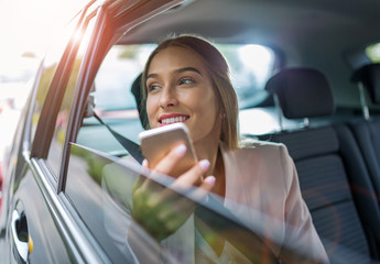 Woman with smart phone in a car
 - obrazy, fototapety, plakaty