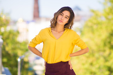 Portrait of a young woman in bright yellow blouse with hands on her hips