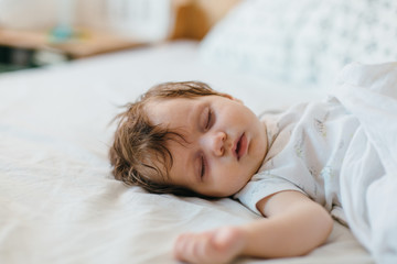 Obraz na płótnie Canvas Portrait of cute baby girl sleeping on white bedding .