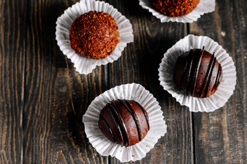 Chocolate cakes on a wooden table in powdered sugar. Selective focus. Dark style background..Top view