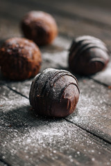 Chocolate cakes on a wooden table in powdered sugar. Selective focus. Dark style background.