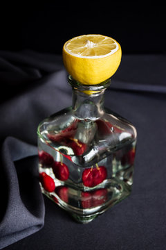 A bottle of water with cherries and lemon.