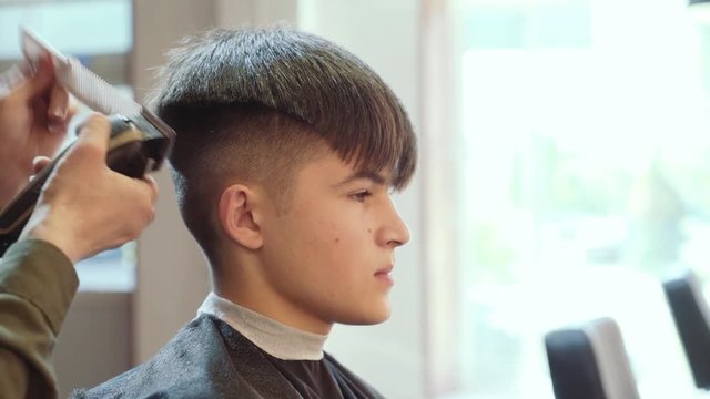 Hairdresser for men. Barbershop. Hair cutting on the side of the young guy's head with a hair clipper