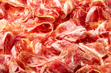 Appetizing slices Iberian ham in the foreground as a texture. Raw meat that becomes an article of...