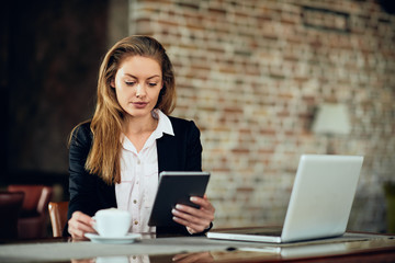 Businesswoman using laptop while sitting in cafeteria. On table laptop and coffee.