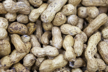 Unrefined peanuts in shell on market counter in daylight.