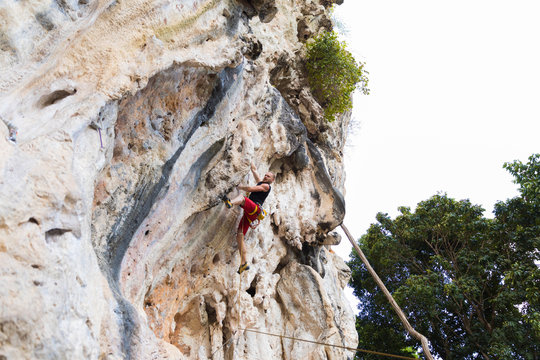 Young man rock climbing on white mountain in Thailand