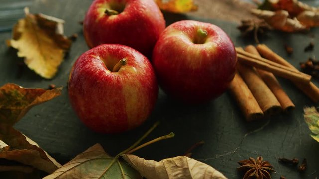 From above shot of sweet ripe apples with shiny skins composed on table with aromatic spices and fallen leaves