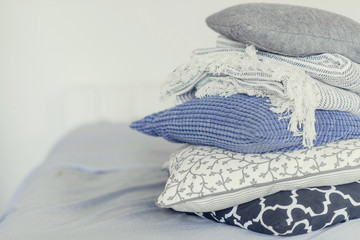 pile of pillows on the edge of the bed, in gray, monochrome