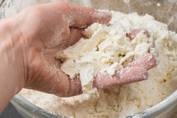 hand mixing the flour and butter in glass bowl