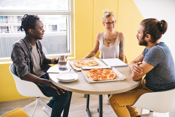 mixed group of colleagues having pizza while working