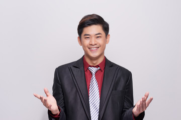 Handsome and well dressed businessman in a suit, tie and vest, standing against a white background smiling towards camera.