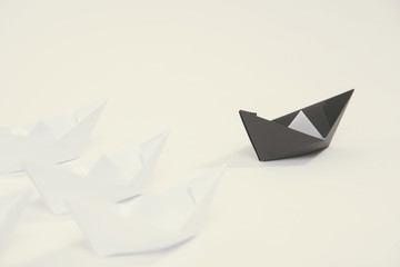 creative black paper ship among white. concept leadership different.