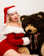 sexy christmas girl embraces with a big teddy bear. blonde woman dressed as Santa
