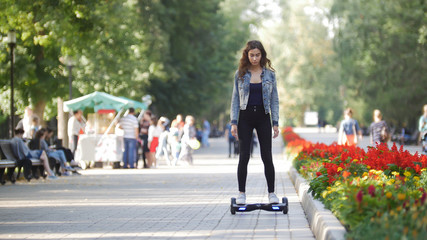 Naklejka premium Young beautiful girl rides a gyro in the park on a summer day