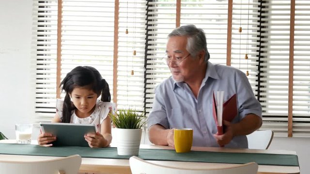 Senior man reading book with girl at home. people with family, lifestyle. people with family, lifestyle, technology concept. 4k resolution